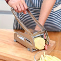 Stainless steel vegetable cutter slicing potatoes on a wooden countertop