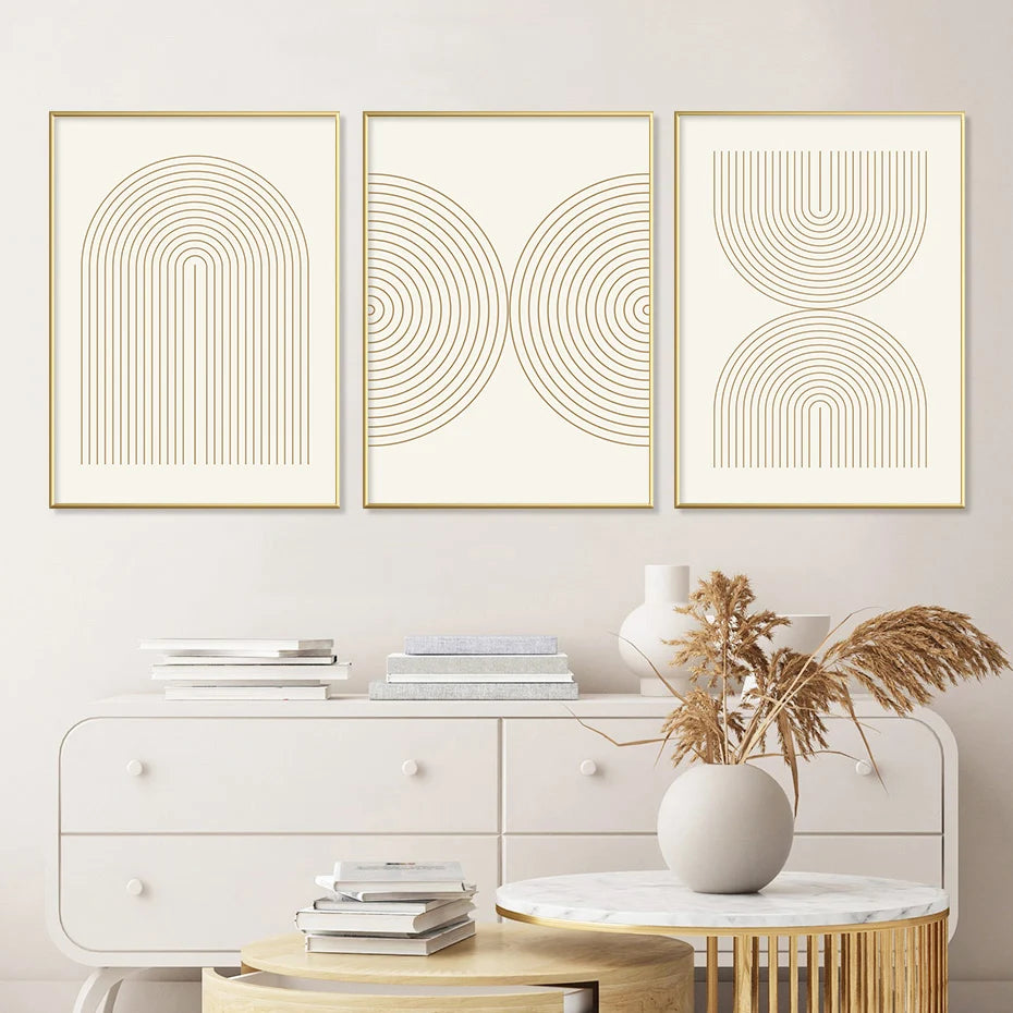Three abstract wall art prints with gold frames on a light gray wall above a white dresser.