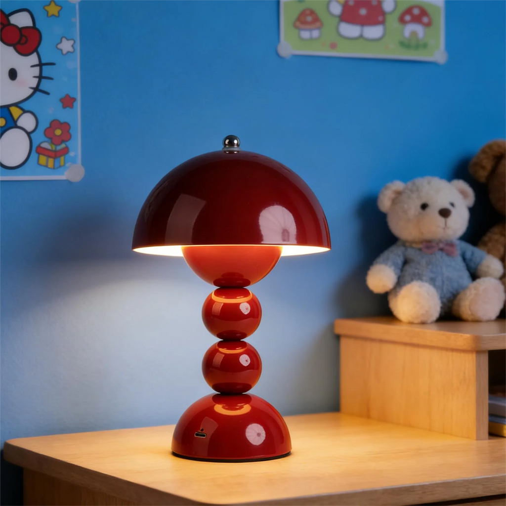 Red table lamp on a wooden surface with a blue wall and teddy bear in the background