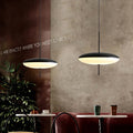 Modern pendant lights hanging above café tables with soft white disc-shaped shades