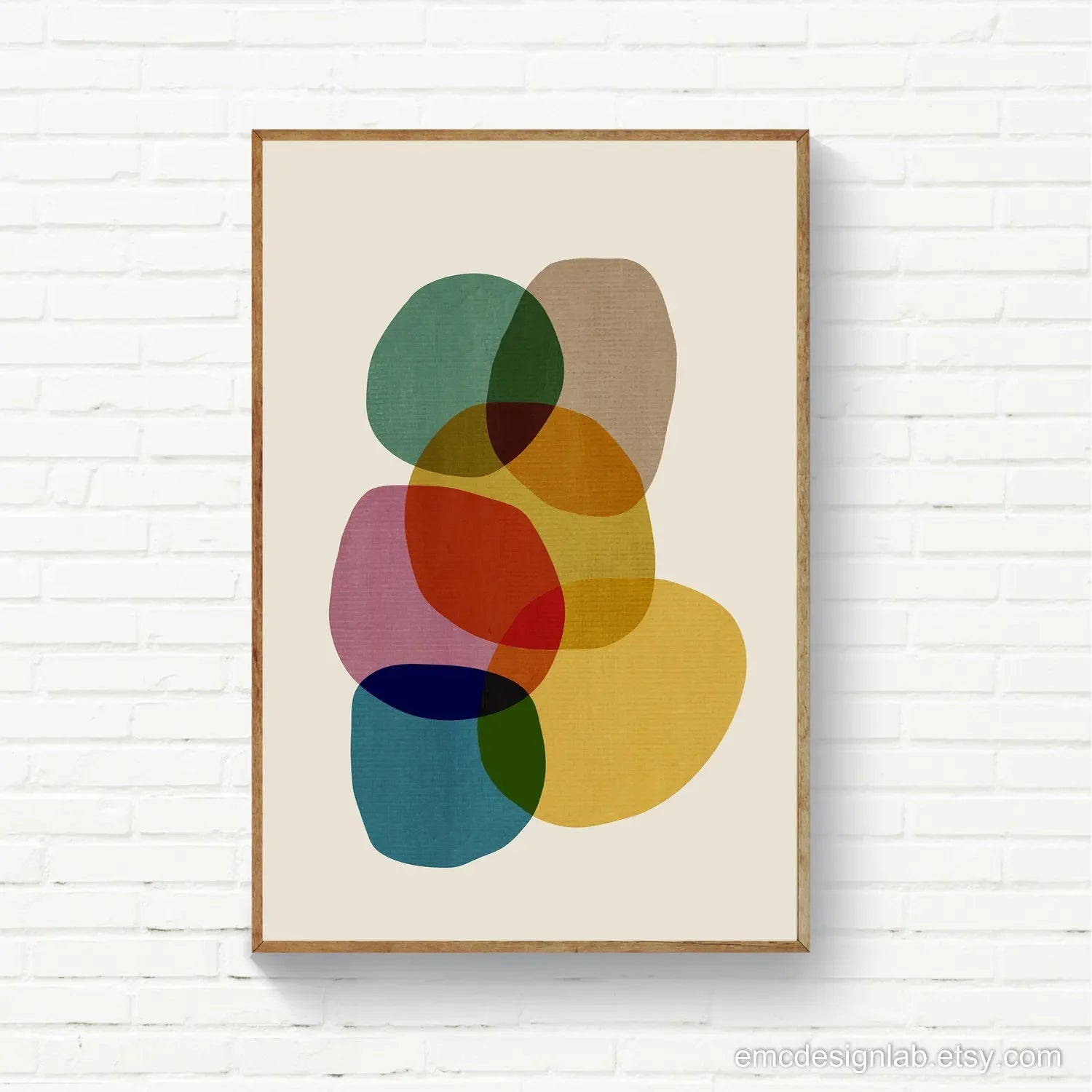 Framed abstract art print with colorful shapes on a white brick wall.