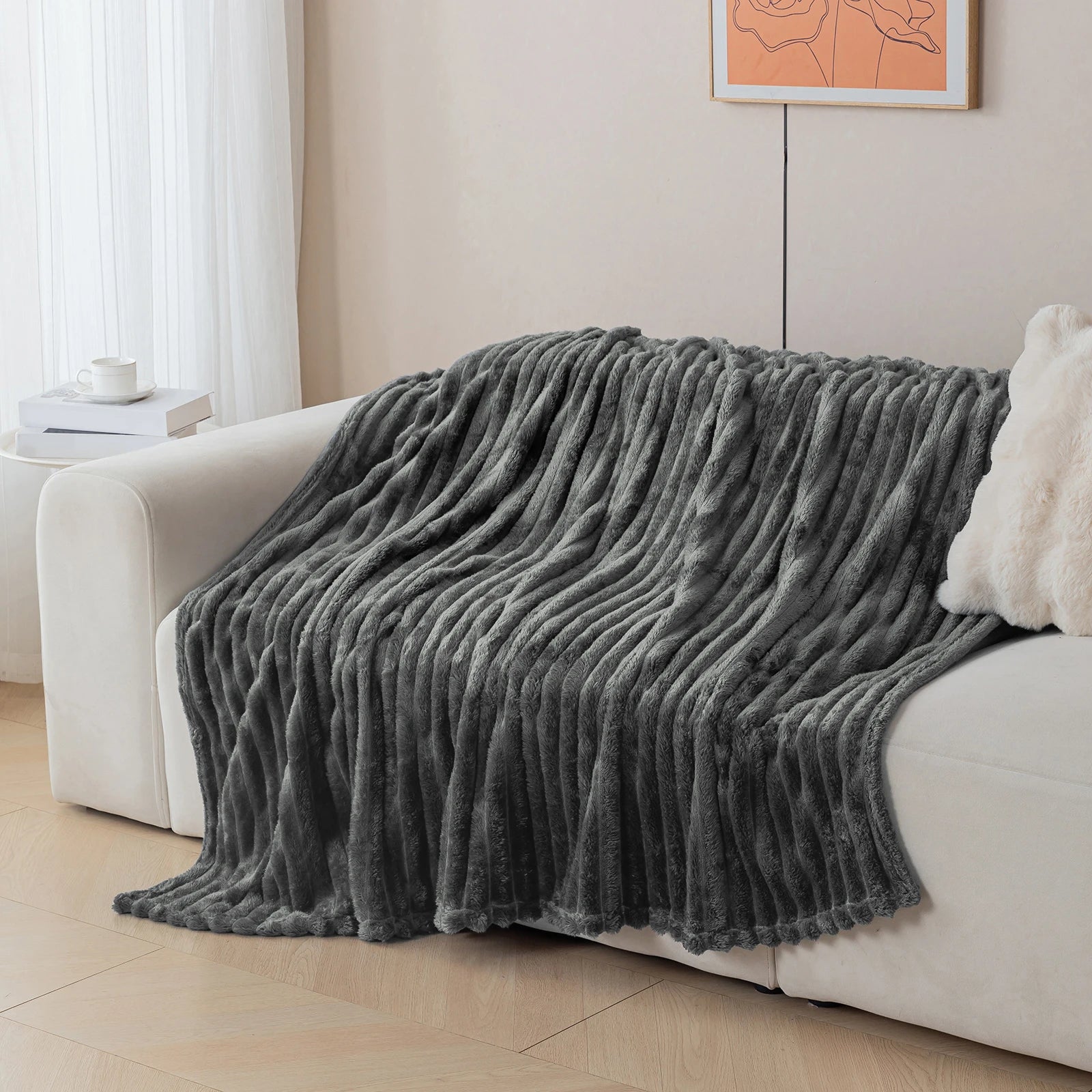 Gray blanket draped over a white sofa in a living room setting.