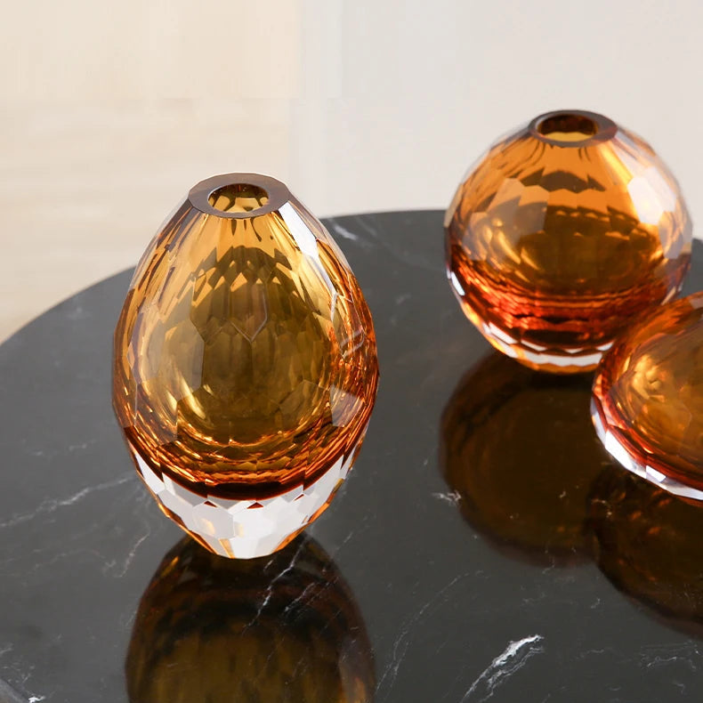 Three amber-coloured glass vases on a dark surface with a light background