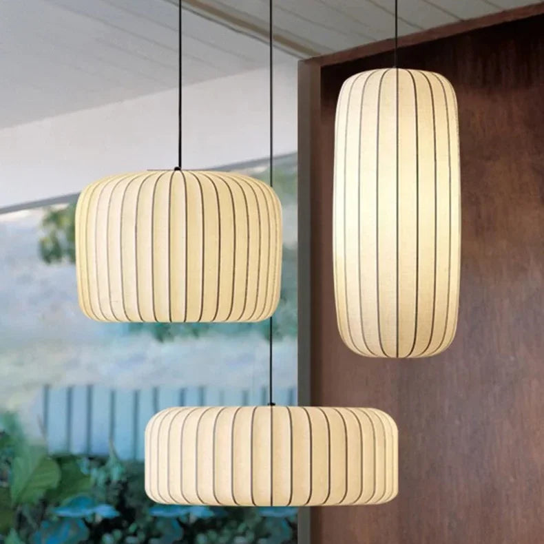 Three pendant lights hanging in a room with a wooden wall and plants.