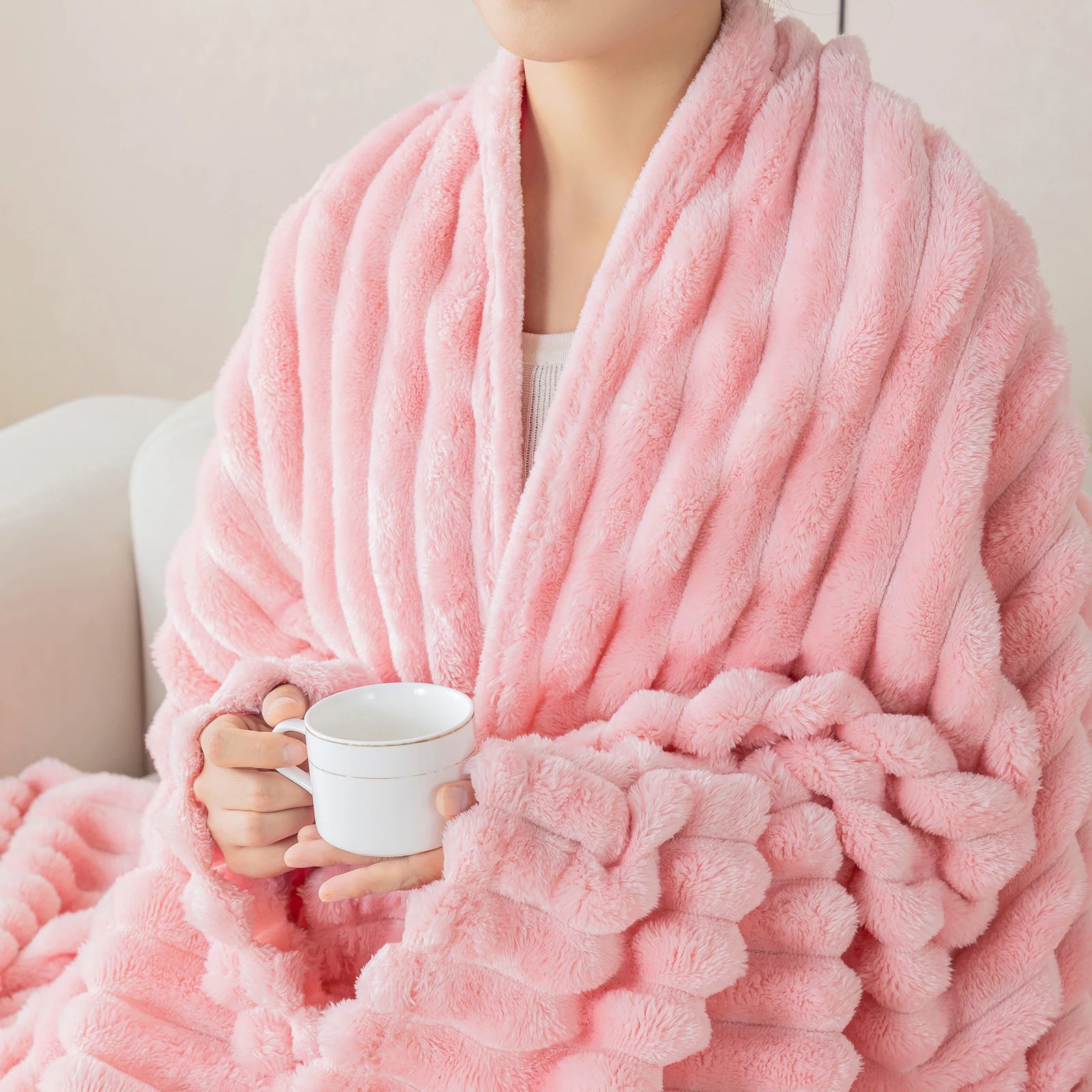 Person wearing a pink robe holding a white mug on a neutral background