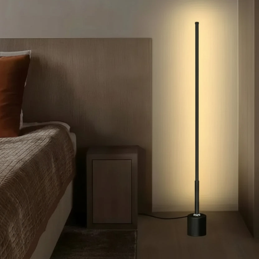 Slim black LED floor lamp casting warm ambient wall light