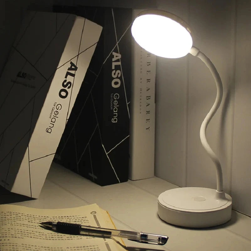 Desk lamp on a desk with books and a pen in the background
