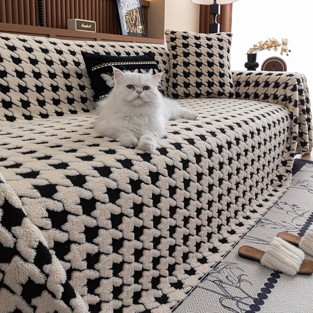 White cat sitting on a black and white patterned sofa with a geometric design.