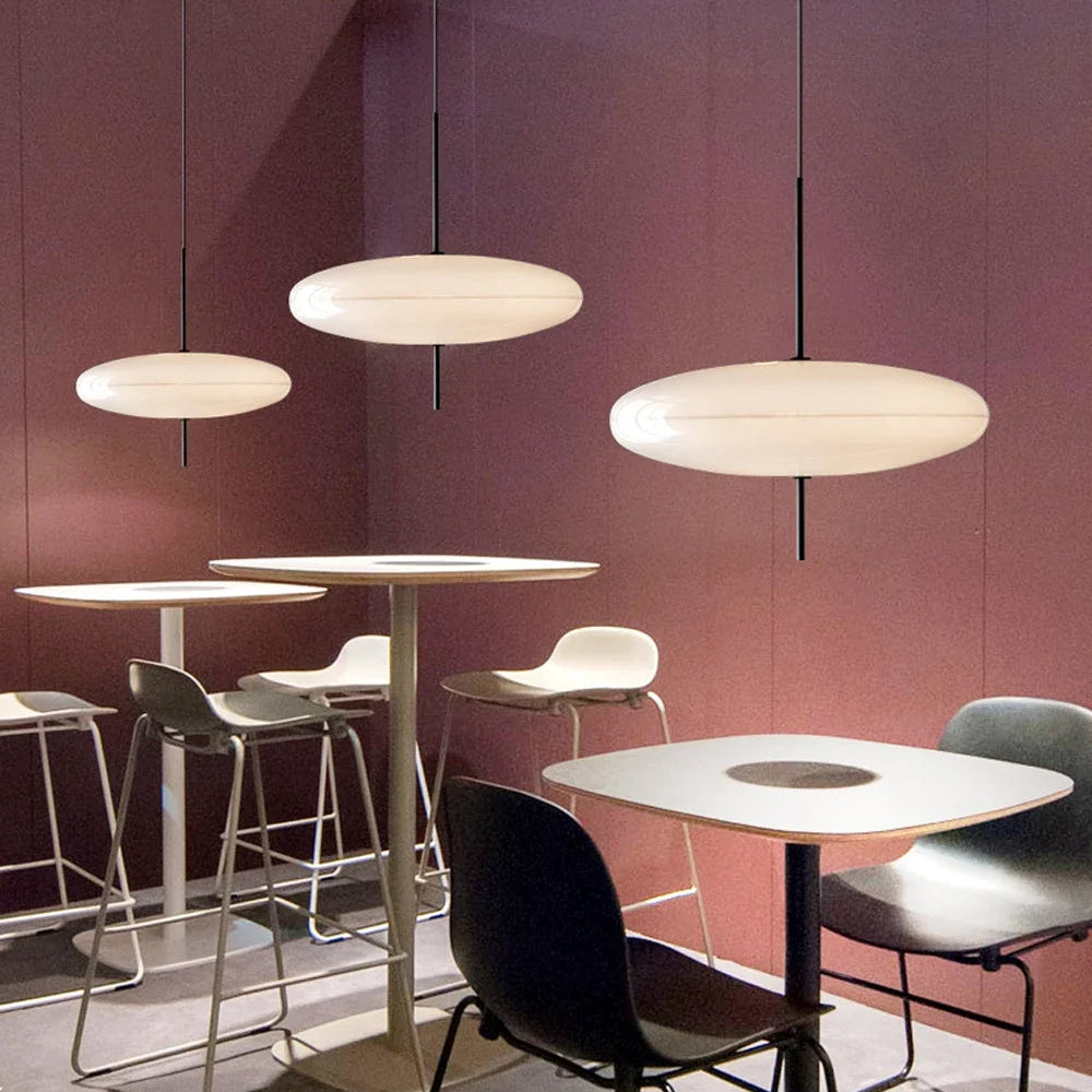 Modern pendant lights hanging above café tables with soft white disc-shaped shades