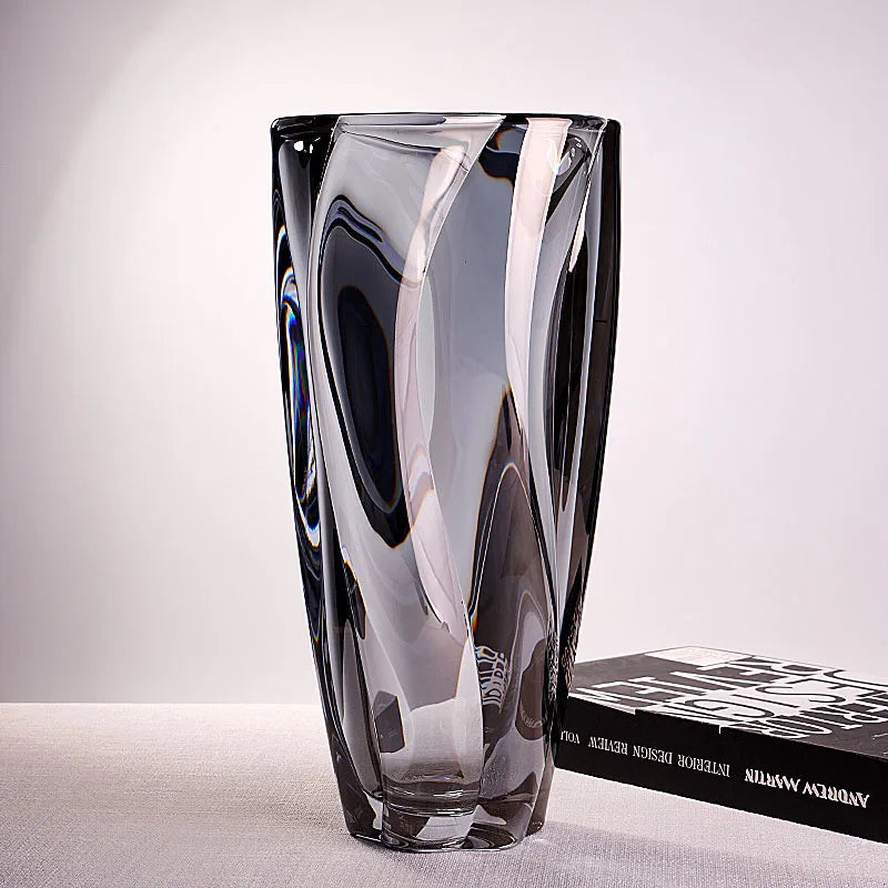 A heavyweight smoked grey crystal glass vase with a spiralled design on a white tabletop.