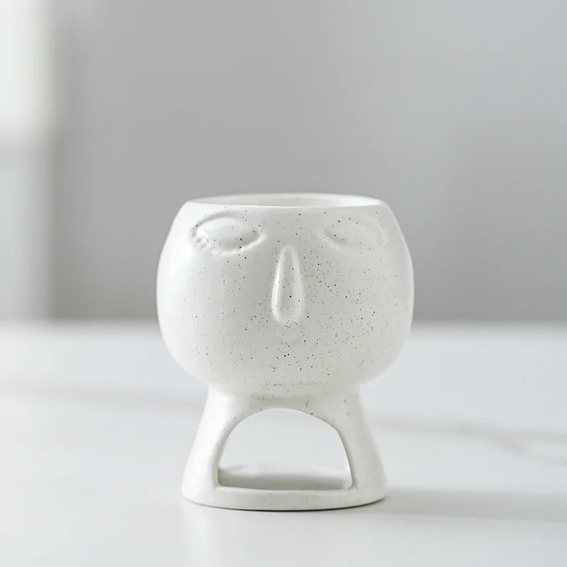 White ceramic incense burner with face design on a light gray background