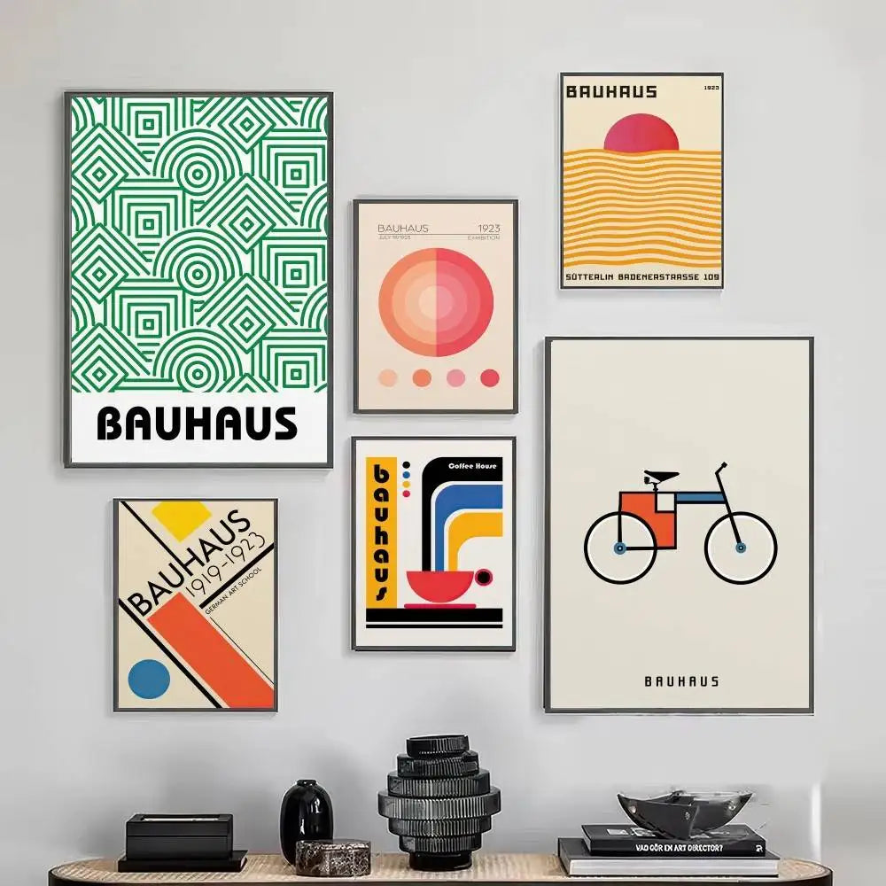 Collection of Bauhaus-themed posters on a wall with decorative items on a table below.