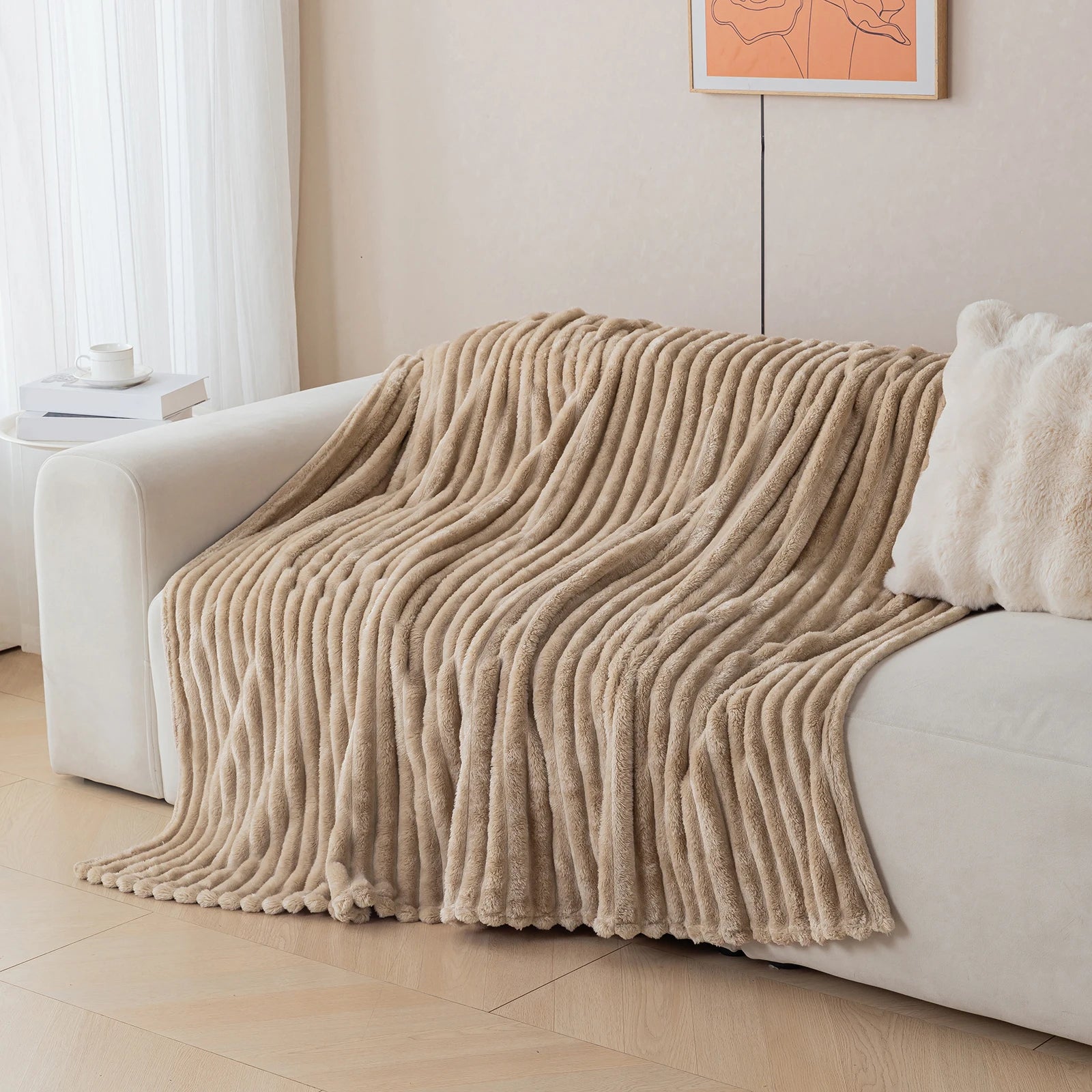 Beige blanket draped over a white sofa in a living room setting.
