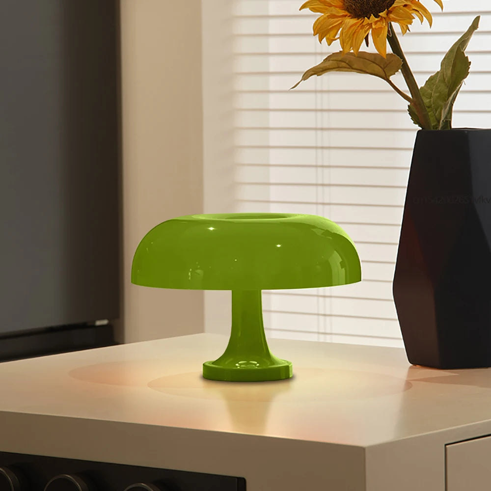 Green lamp on a surface with a vase of sunflowers in the background