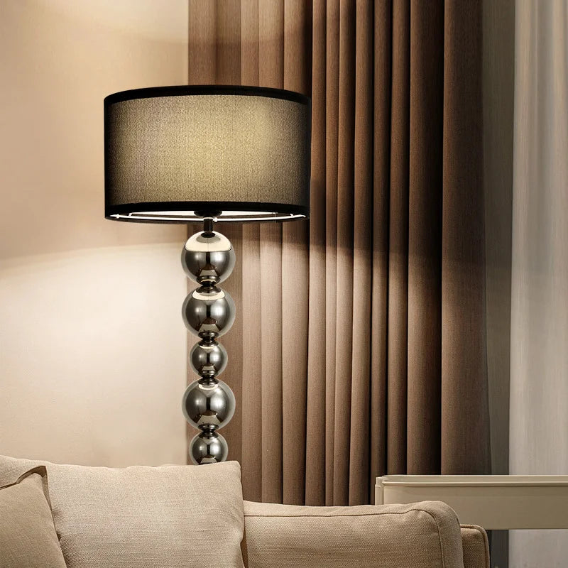 Decorative lamp with a black shade and metallic base in a living room setting.