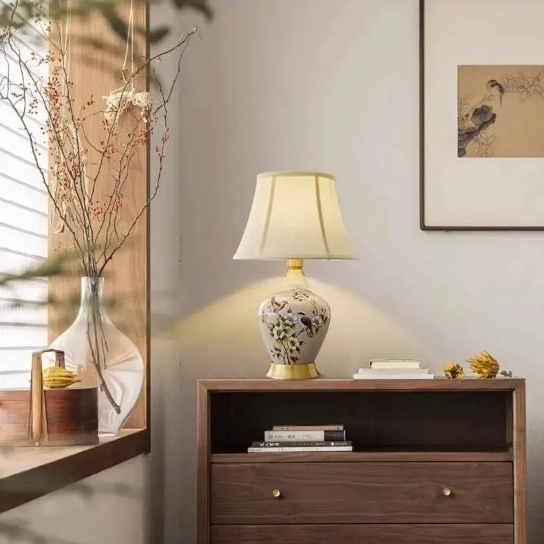 Decorative lamp on a wooden side table with a neutral wall and framed picture in the background.