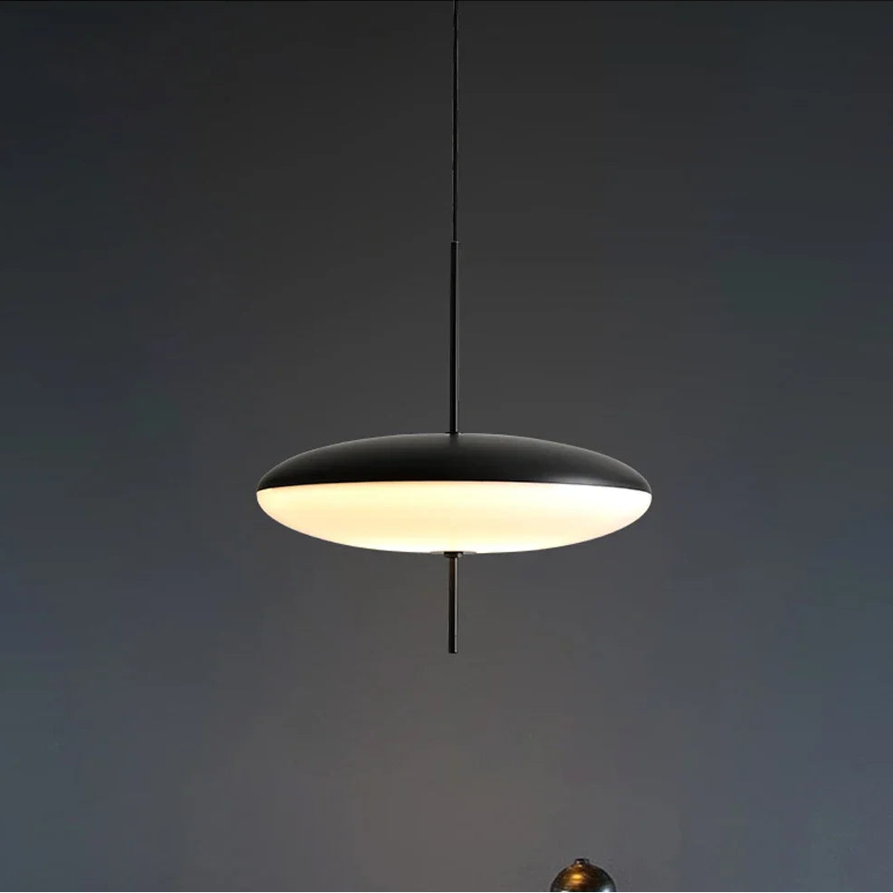 Modern pendant light hanging above a table with decorative items against a dark wall.