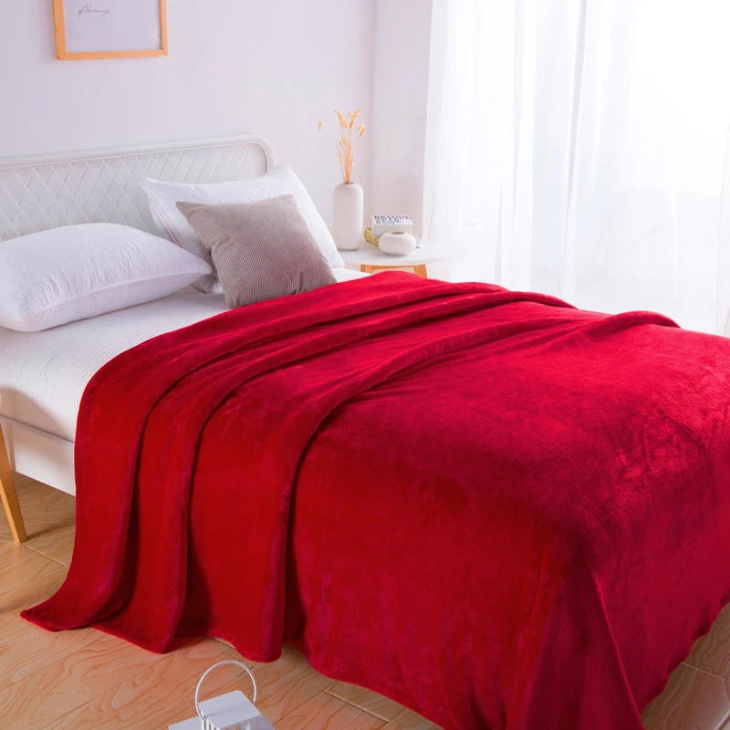 Red plush blanket spread over a bed with white and taupe pillows