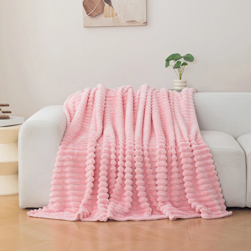 Pink blanket draped over a sofa in a living room setting
