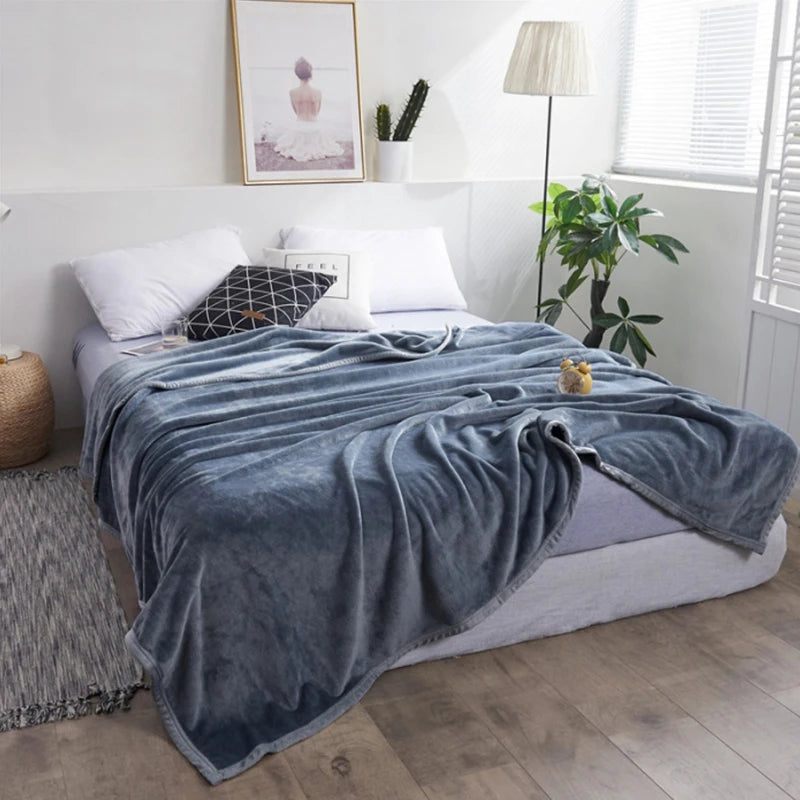Grey blanket draped over a bed in a bedroom setting with decor elements.
