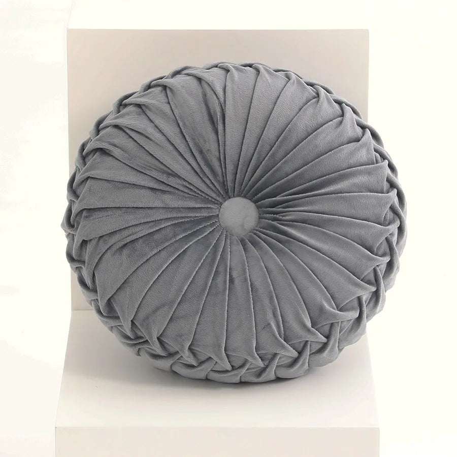 Round grey cushion with pleated texture on a light background