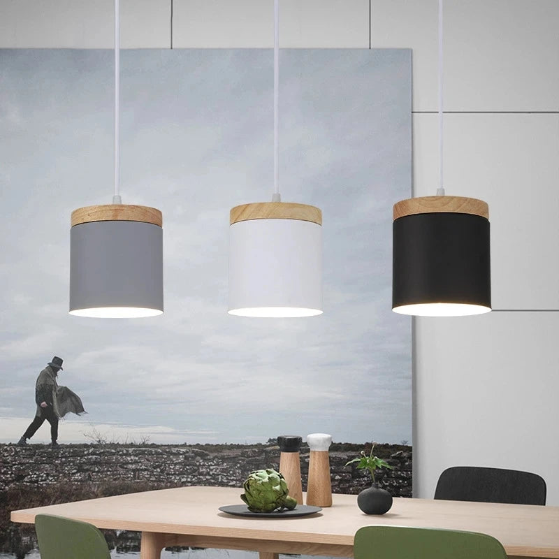 Three pendant lights hanging above a dining table with a scenic painting in the background.