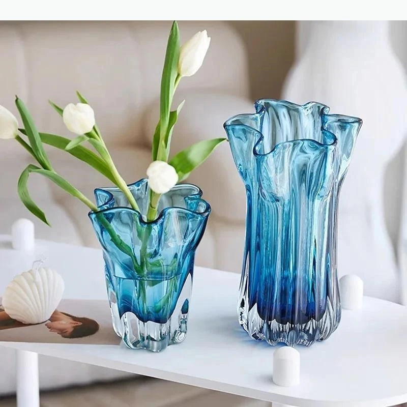 Two blue glass vases with tulips on a white surface