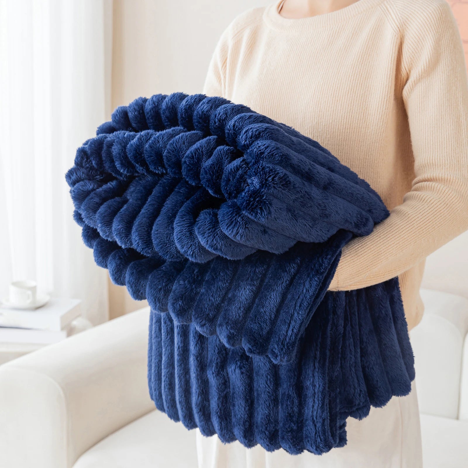 Person holding a blue fluffy blanket in a bright room
