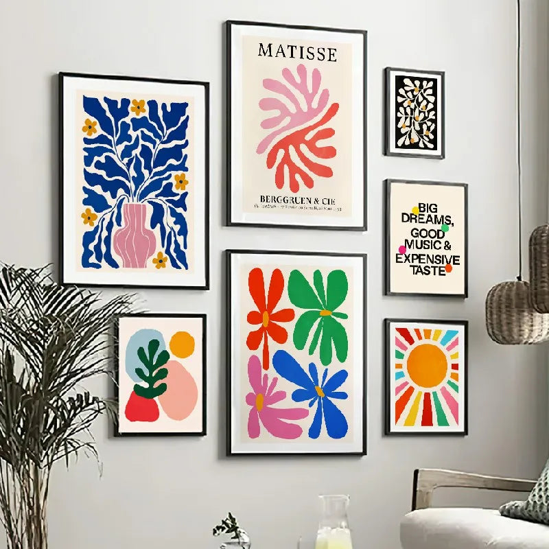 Colourful abstract art prints on a wall with a plant and chair in the foreground.