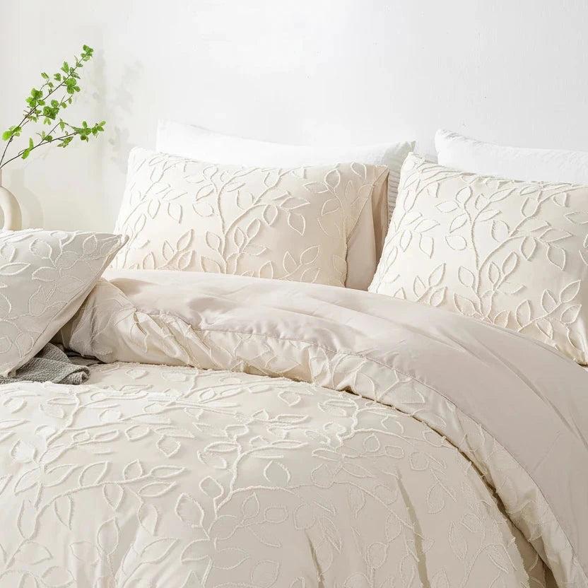 A cream-textured bedding set with matching pillows on a bed.