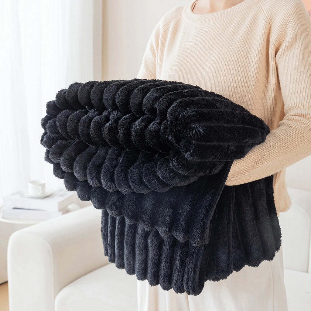 Person holding a black fluffy blanket in a home setting