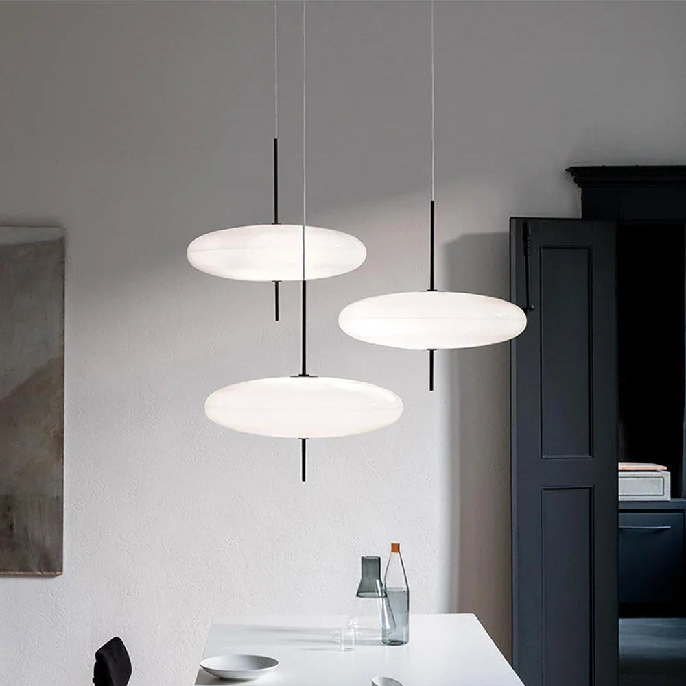 Modern pendant lights hanging above café tables with soft white disc-shaped shades