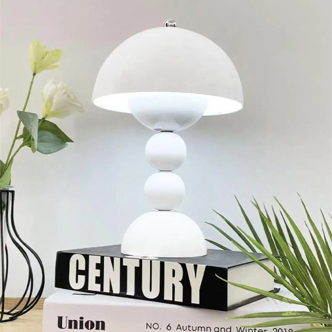White table lamp on a stack of books with plants in the background
