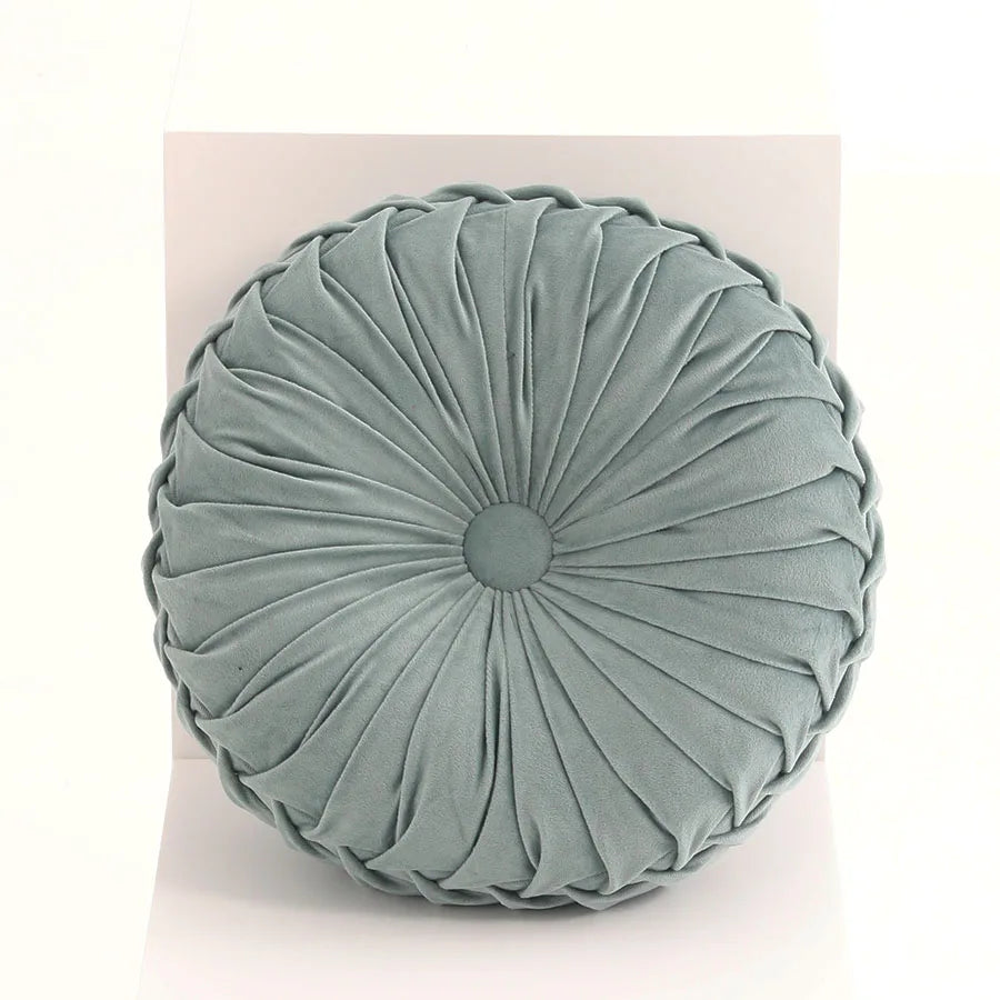 Round pleated cushion in a light green color on a white background