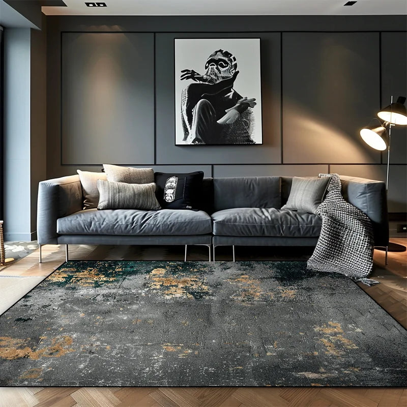 Dark charcoal abstract area rug with gold and teal dust detail in a moody modern living room with grey sofa