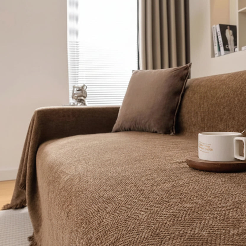 Chocolate-brown soft chenille throw with fringe edges, styled in a cosy interior setting.