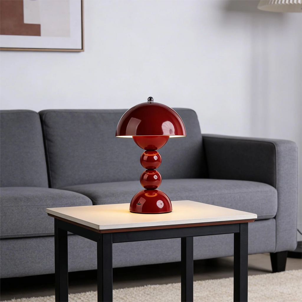 Red table lamp on a coffee table with a gray sofa in the background