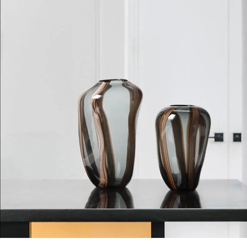 Two decorative vases on a black surface with a white wall background