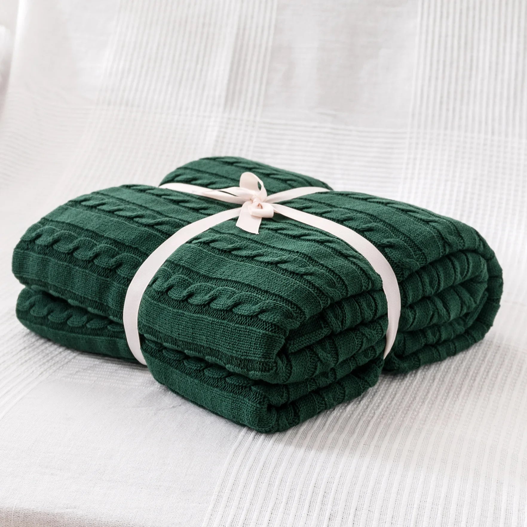 Folded green blanket tied with a white ribbon on a white background