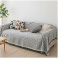 Light grey sofa and chair cover with textured woven pattern and fringe detail