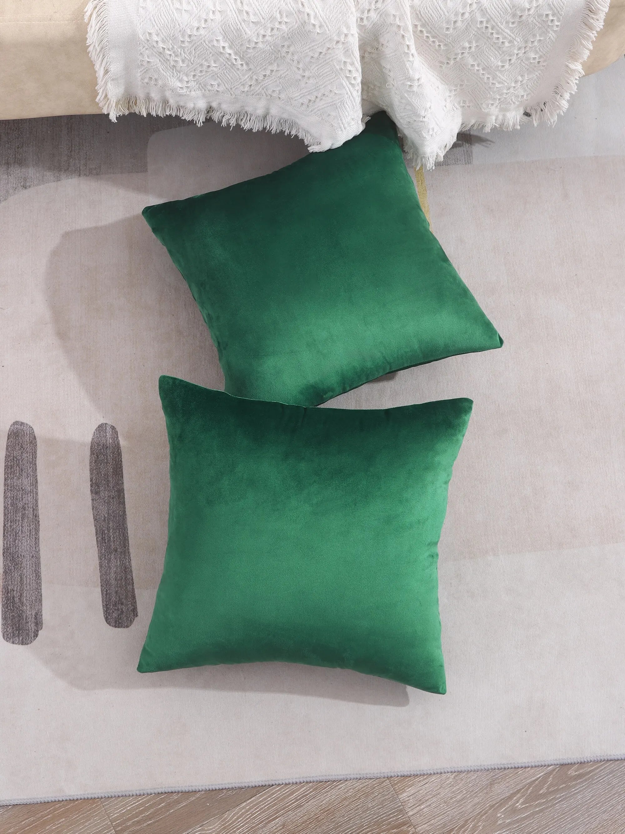 Two green pillows on a light-colored couch with a white blanket.