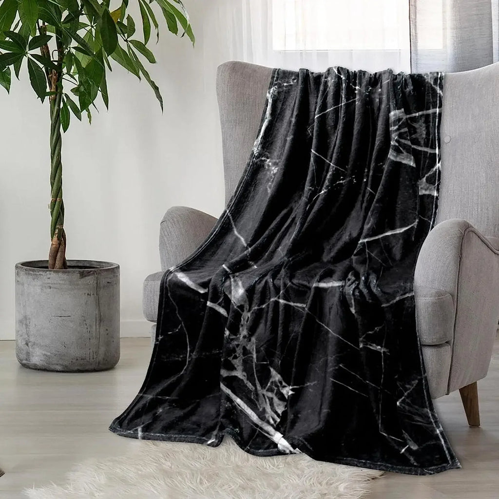 Black marble polyester throw blanket draped over a grey armchair