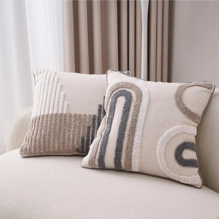 Decorative pillows with geometric patterns on a beige sofa.
