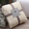 Folded beige blanket with a label on a textured surface