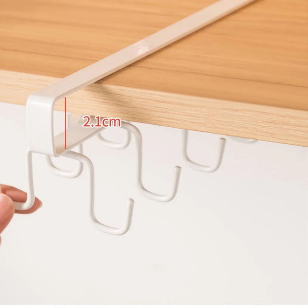 Hand holding a white hook under a wooden cabinet with a measurement label