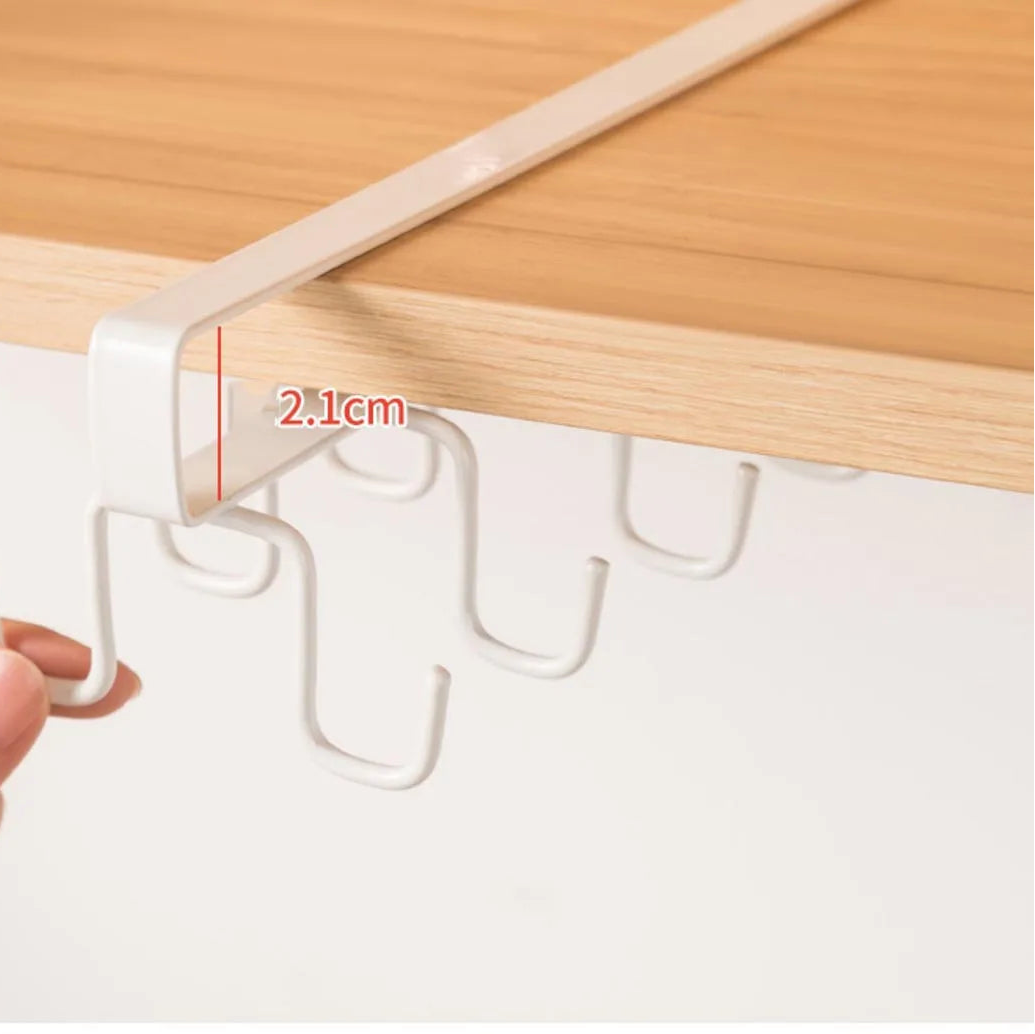 Hand holding a white hook under a wooden cabinet with a measurement label