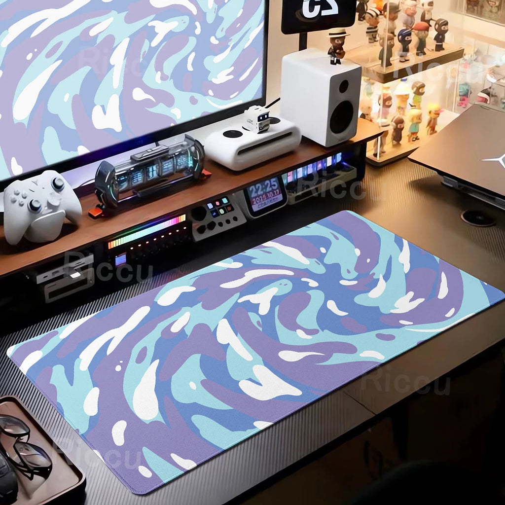 Gaming desk setup with a large mouse pad featuring a blue and purple abstract design.