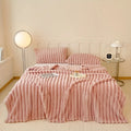 Pink textured bedspread set on a bed in a bedroom with lamps and nightstands.