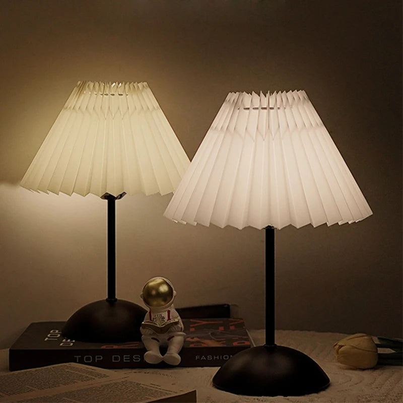 Two pleated table lamps on a surface with a soft glow.
