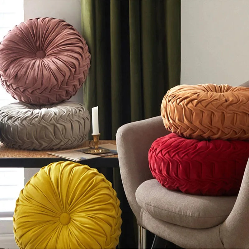 Colourful, round, textured cushions on a chair and table against a curtain backdrop